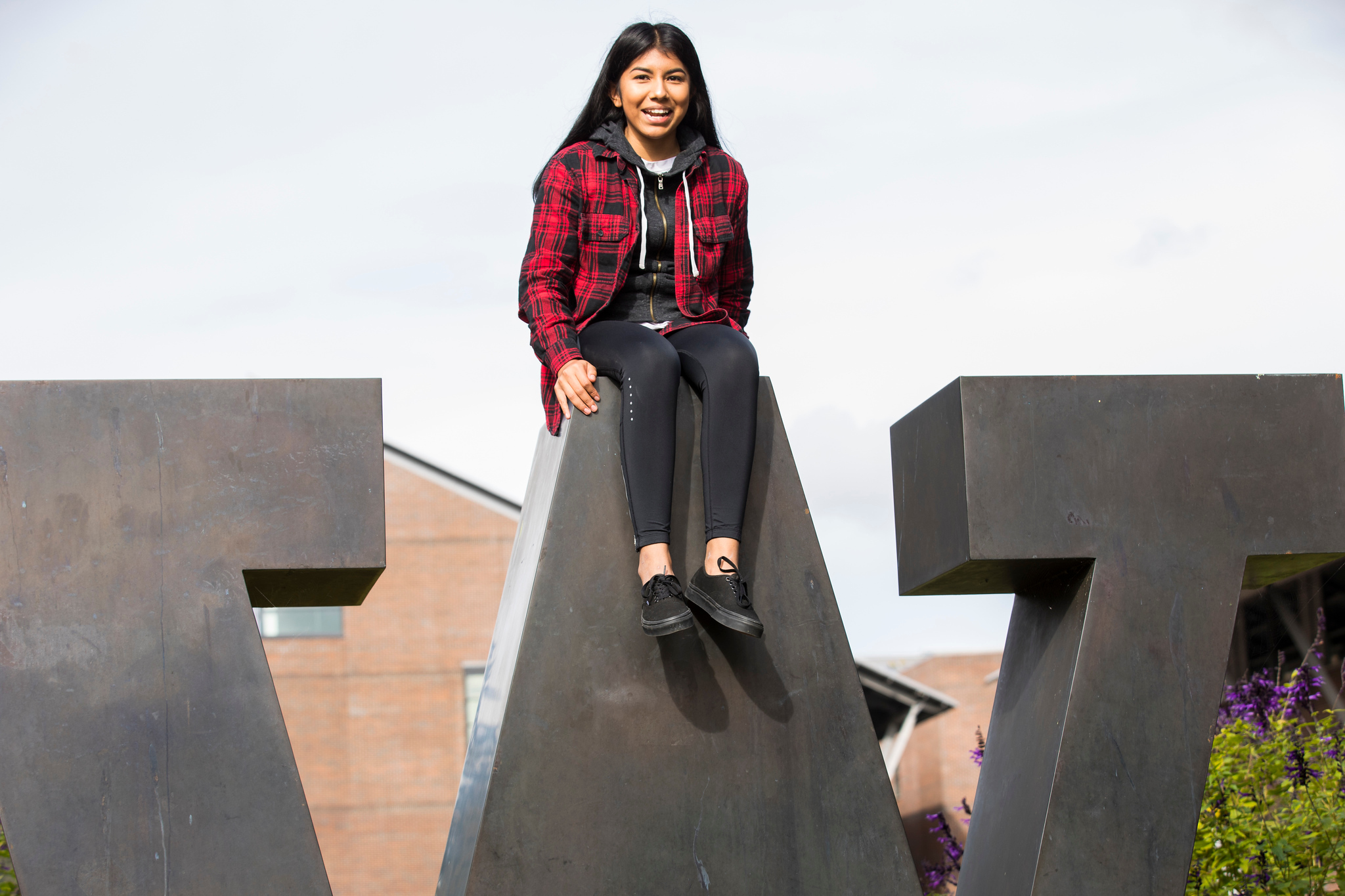 A student sits atop the UW logo