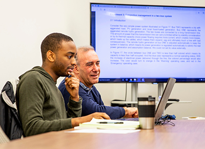 A faculty member guides a student on a research project