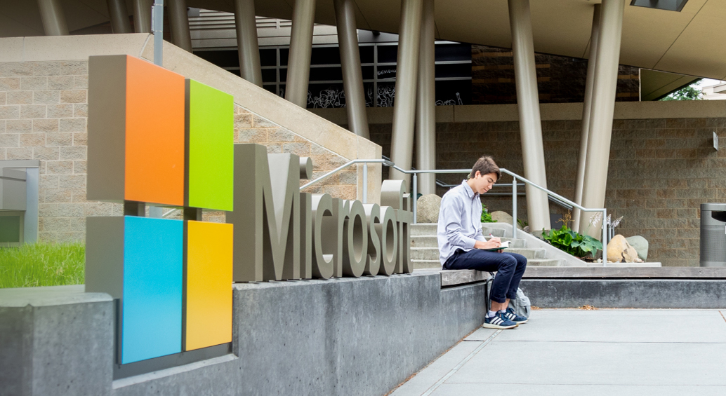 A person sits next to a Microsoft sign