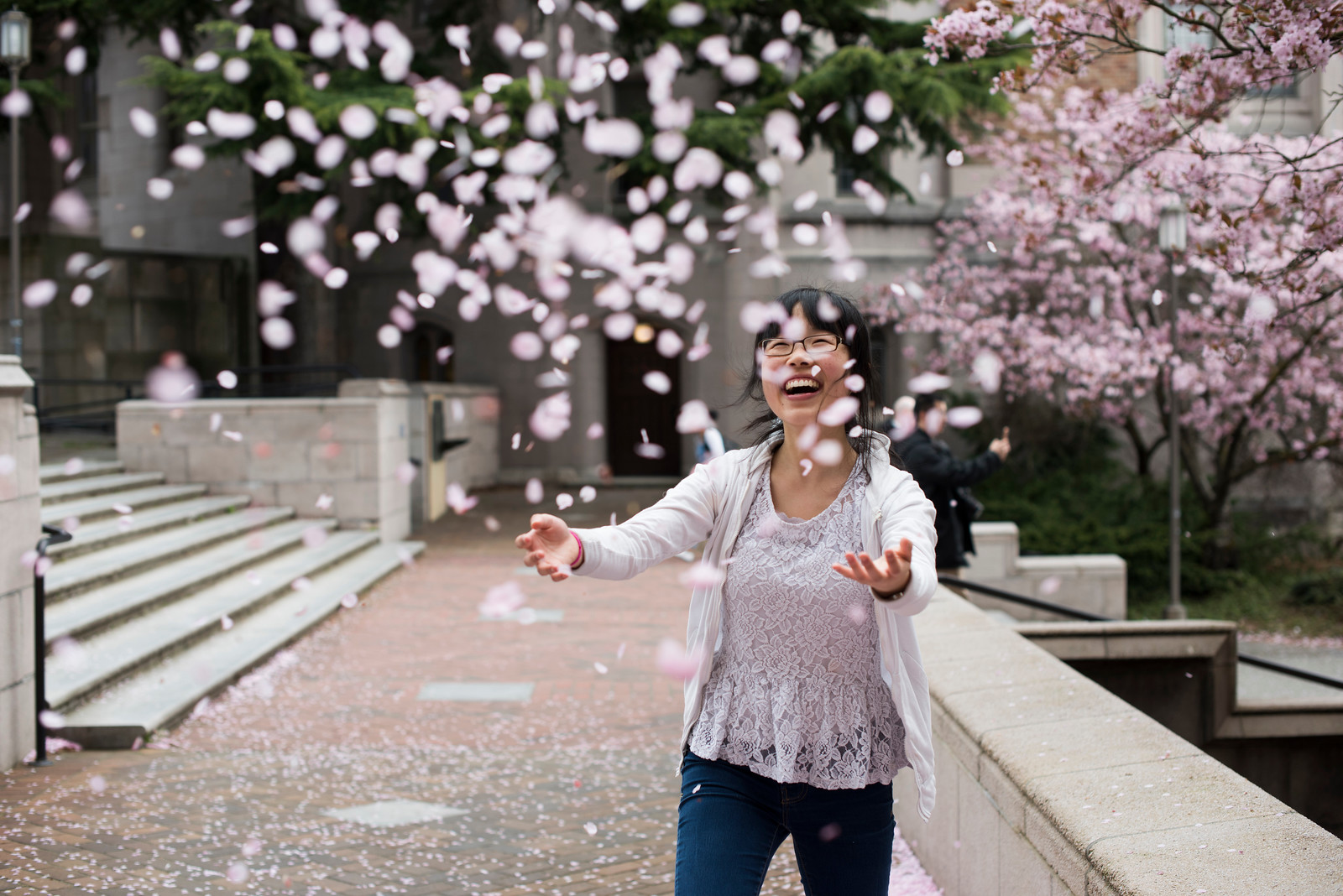 Student throwing cherry blossom petals in air