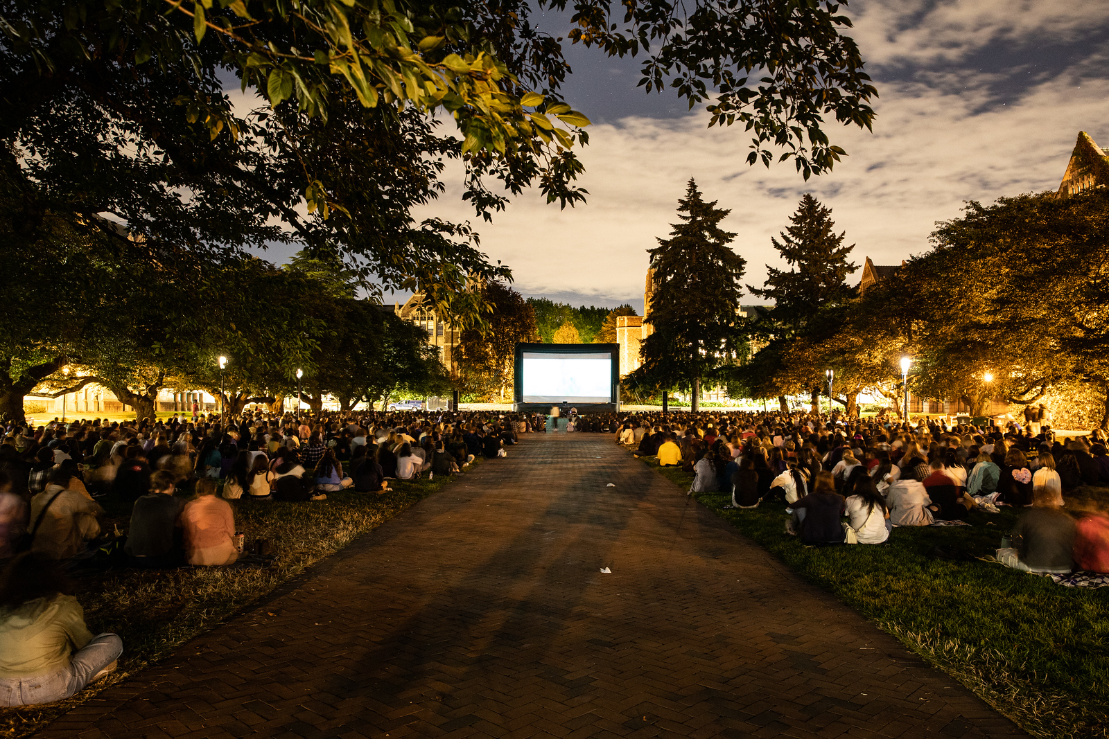 Students gather in the quad to watch a movie at dusk