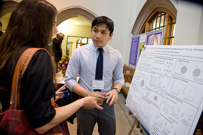 A student presents a research poster in the Mary Gates commons
